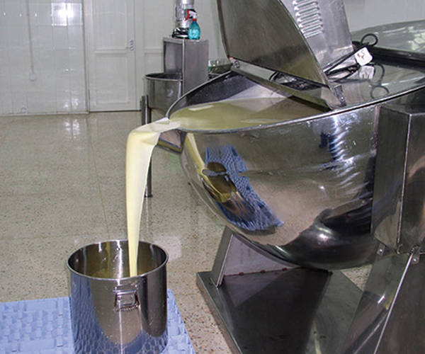 Royal jelly being poured from industrial processing equipment